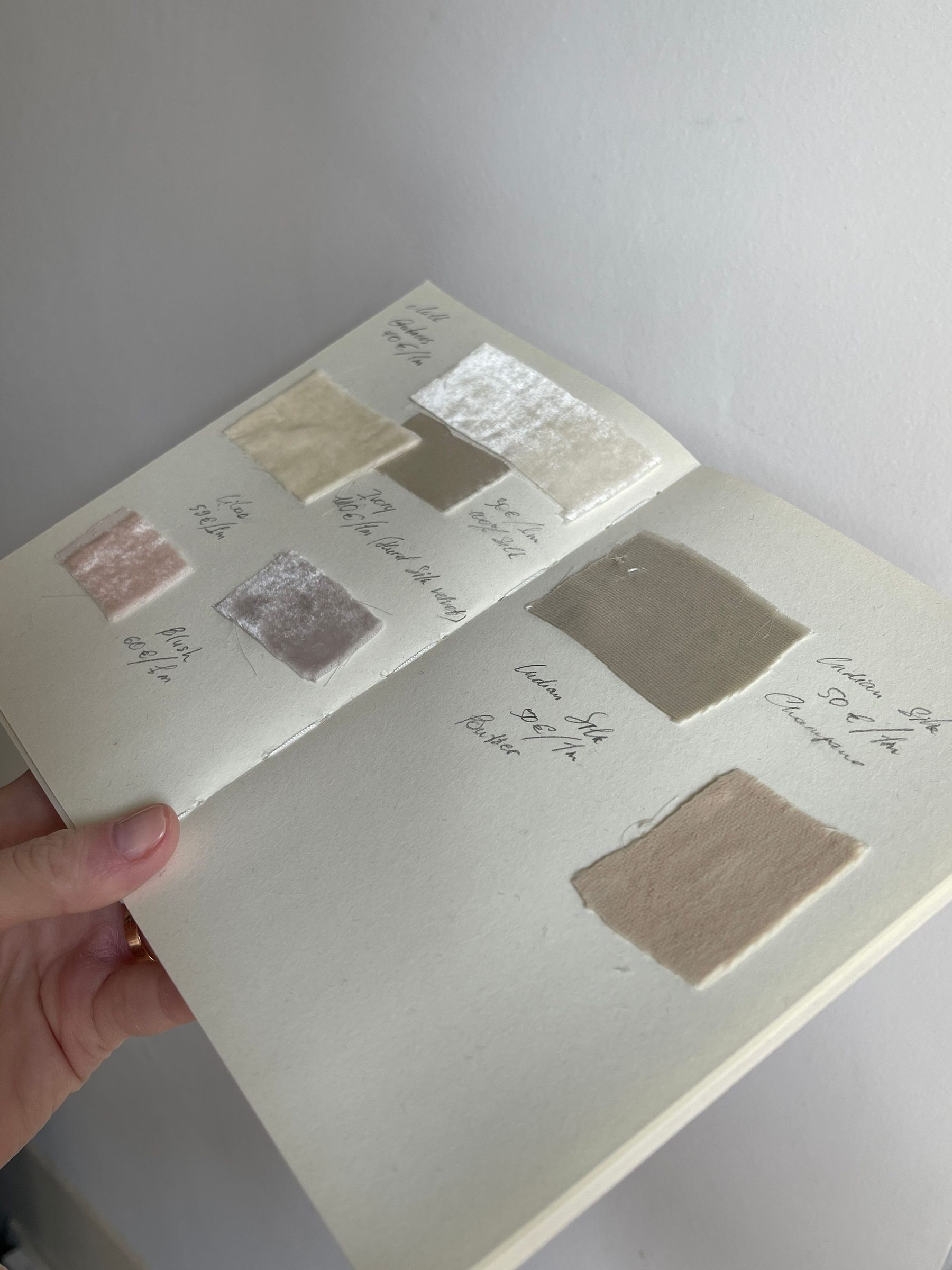A hand holding a sample card of paint and fabric finishes during scheme design